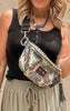 Close-up of camouflage Makeup Junkie sidekick bag with gold zipper and tassel, worn across the body.