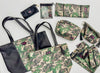 Assorted camo print Makeup Junkie bags including totes, clutches, and cosmetic organizers with black detailing and tassel zippers.