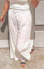 Woman modeling khaki linen blend palazzo pants with a drawstring waist, styled with a ribbed white tank and black studded sandals.