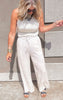 Close-up of khaki drawstring palazzo pants featuring a high waist and soft linen texture, styled casually with bold bangles.