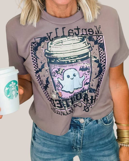 Person wearing a graphic t-shirt with a coffee cup design, holding a Starbucks cup.