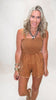 Woman wearing a brown romper with a plain background